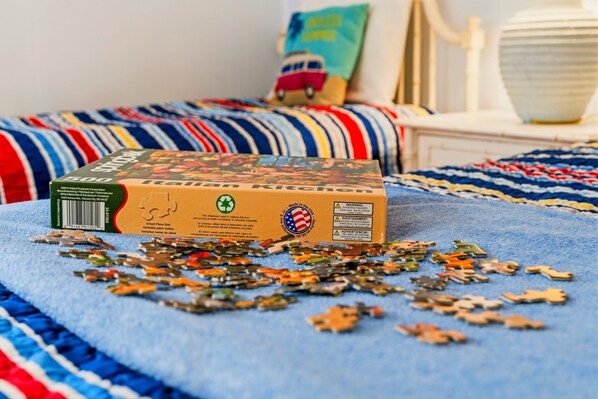A puzzle box on a bed with scattered puzzle pieces. - Eat, Beach, Sleep and Repeat at Ocean Pier III 128 (North Myrtle Beach)