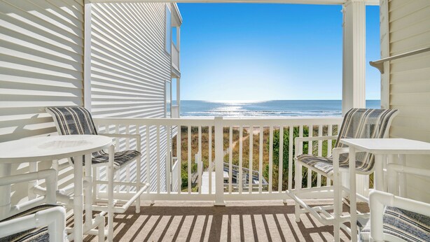A covered outdoor area with white furniture and a view of the ocean.
