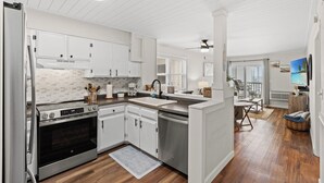 A modern kitchen with white cabinetry, a stainless steel oven, and a large island with a sink.