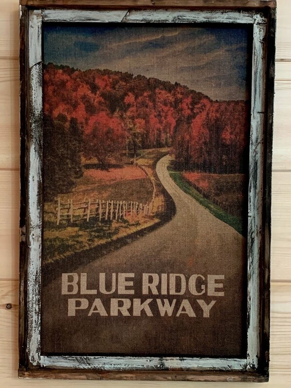 A vintage sign for Blue Ridge Parkway with a winding road and autumn foliage.