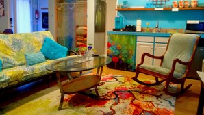 Ein Wohnzimmer mit einer Couch, einem Glastisch, einem gemusterten Teppich und zwei Sesseln.