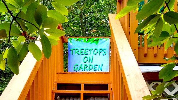 Eine hölzerne Konstruktion mit einem Schild, auf dem 'TREETOPS ON GARDEN' steht.