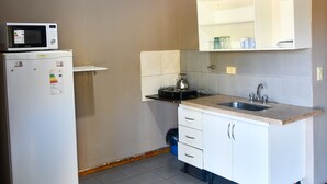 Cocina compacta con refrigerador blanco, microondas, pileta y alacenas.