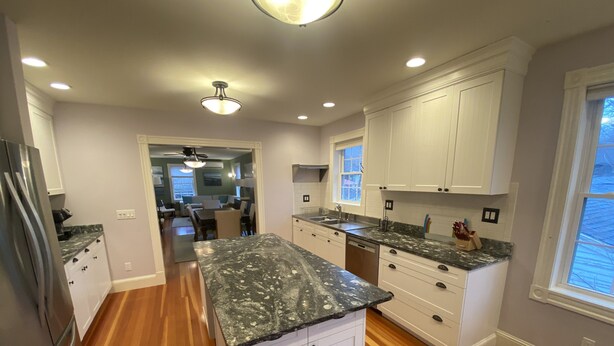 Una cocina moderna con armarios blancos, encimeras de granito y suelo de madera.
