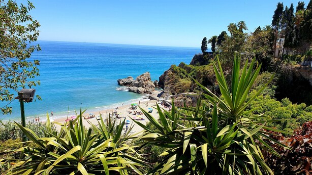 A coastal beach with rocky cliffs, clear blue sea, and lush greenery. - R1345, Carabeo 1-42, Access to the Beach (Nerja)