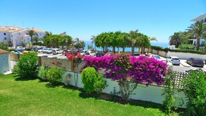 A coastal residential area with parked cars, a white building, and vibrant bougainvillea flowers. - R1345, Carabeo 1-42, Access to the Beach (Nerja)