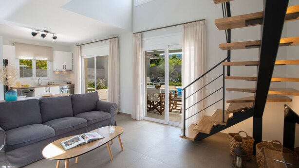 Una sala de estar moderna con un sofá, una mesa de centro y una escalera que conduce a un espacio exterior.