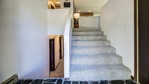 A staircase with a stone base and carpeted steps, leading to a landing with a lamp and a framed picture.