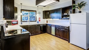 A modern kitchen with dark wooden cabinets, a white refrigerator, and a built-in dishwasher.