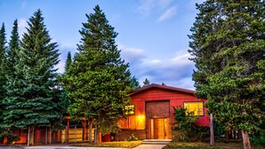 A red building with a brick facade, surrounded by tall evergreen trees.
