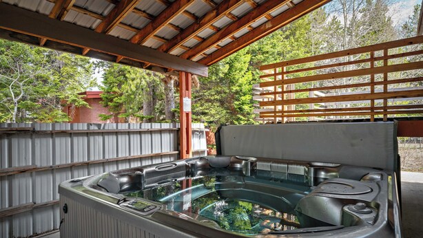 A hot tub with a wooden deck and a metal fence in the background.