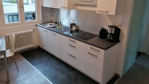Una cocina moderna con armarios blancos, encimera negra, horno empotrado y cafetera.
