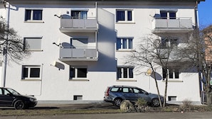 Un edificio residencial de varios pisos con balcones, antenas parabólicas y paneles solares en el techo.