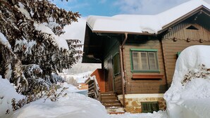 Una casa in legno con tetto innevato e fondamenta in pietra.