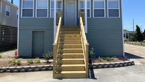 A two-story building with a wooden staircase leading to the front door.