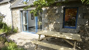 A stone building with a wooden picnic table and a glass door.