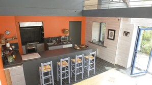 A modern kitchen with a central island, grey chairs, and a dining table.