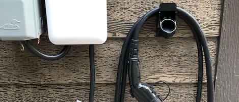 An EV charger connected to a wall-mounted box with a cable.