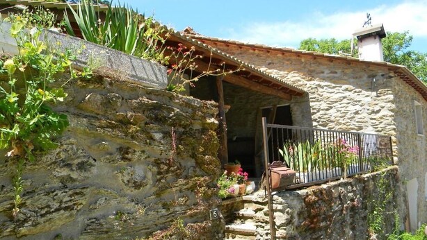 Edifici de pedra amb entrada rústica, un petit porxo i una escala que porta a l'entrada.