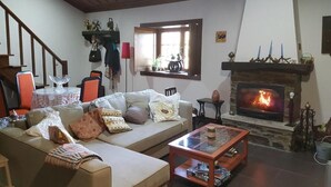 Un saló tranquil amb una llar de foc, un sofà, una taula de centre i una zona de menjador amb cadires i una taula.