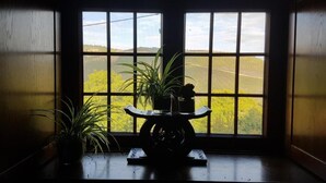 Una habitació amb una finestra gran, una taula petita i una planta en test.