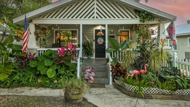 A house with a porch, a flag, and various plants.