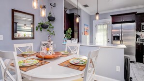 A modern kitchen with a central island, white cabinetry, and stainless steel appliances.