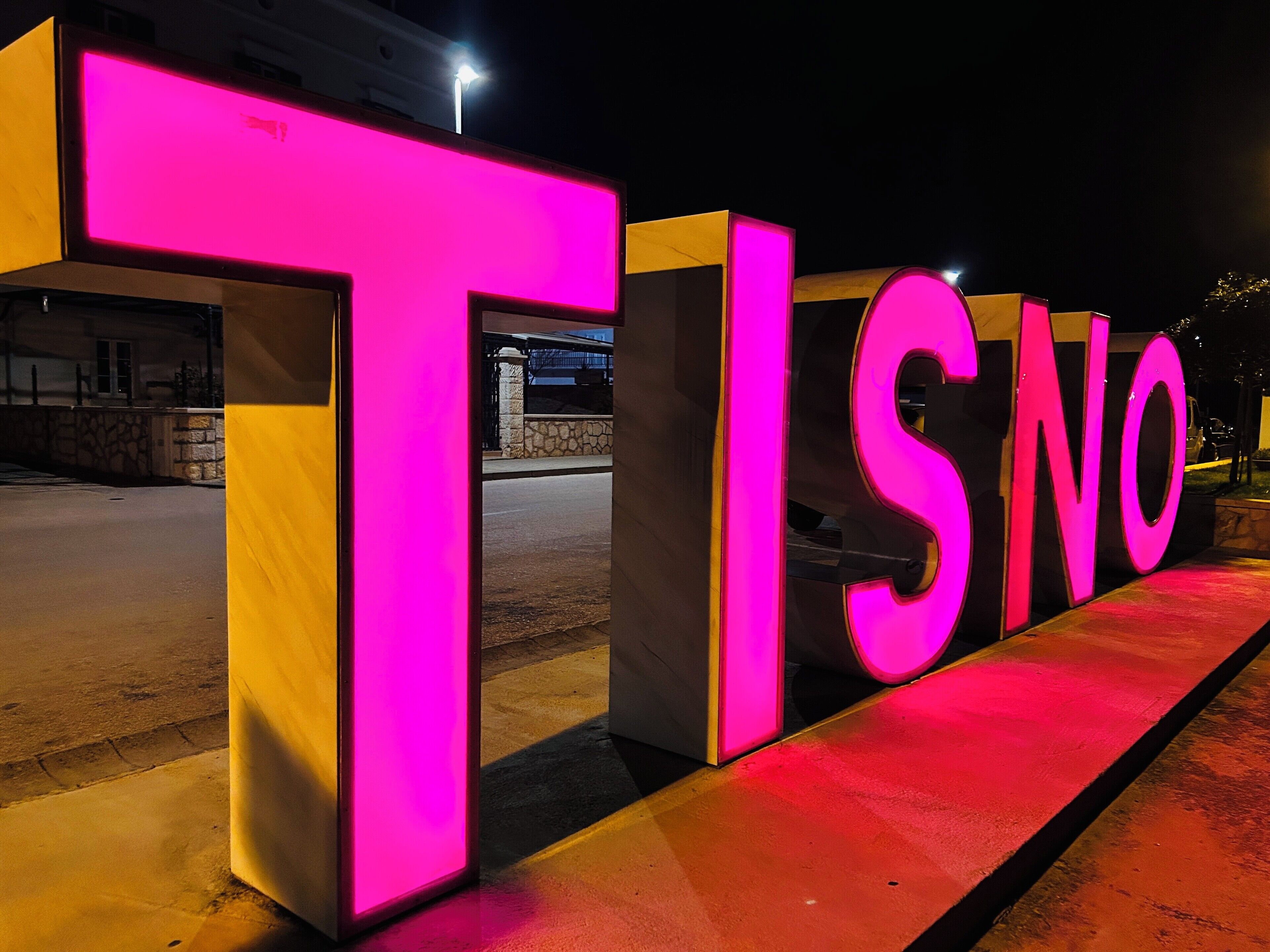 Illuminated letters spelling "TISNO" on a structure.