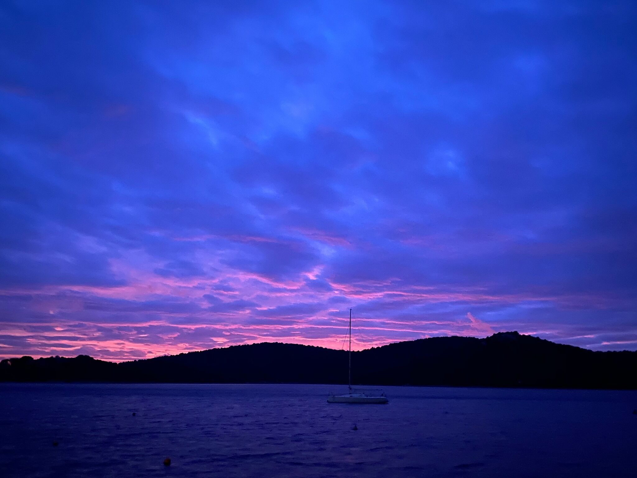 A calm body of water with a sailboat anchored in the center.