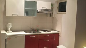 Una cocina compacta con armarios blancos, horno integrado y un lavabo.