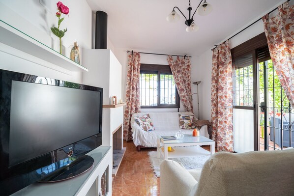 A cozy living room with a flat-screen TV, a sofa, a coffee table, and a fireplace. - Cortijo Rio Torrox (Torrox)