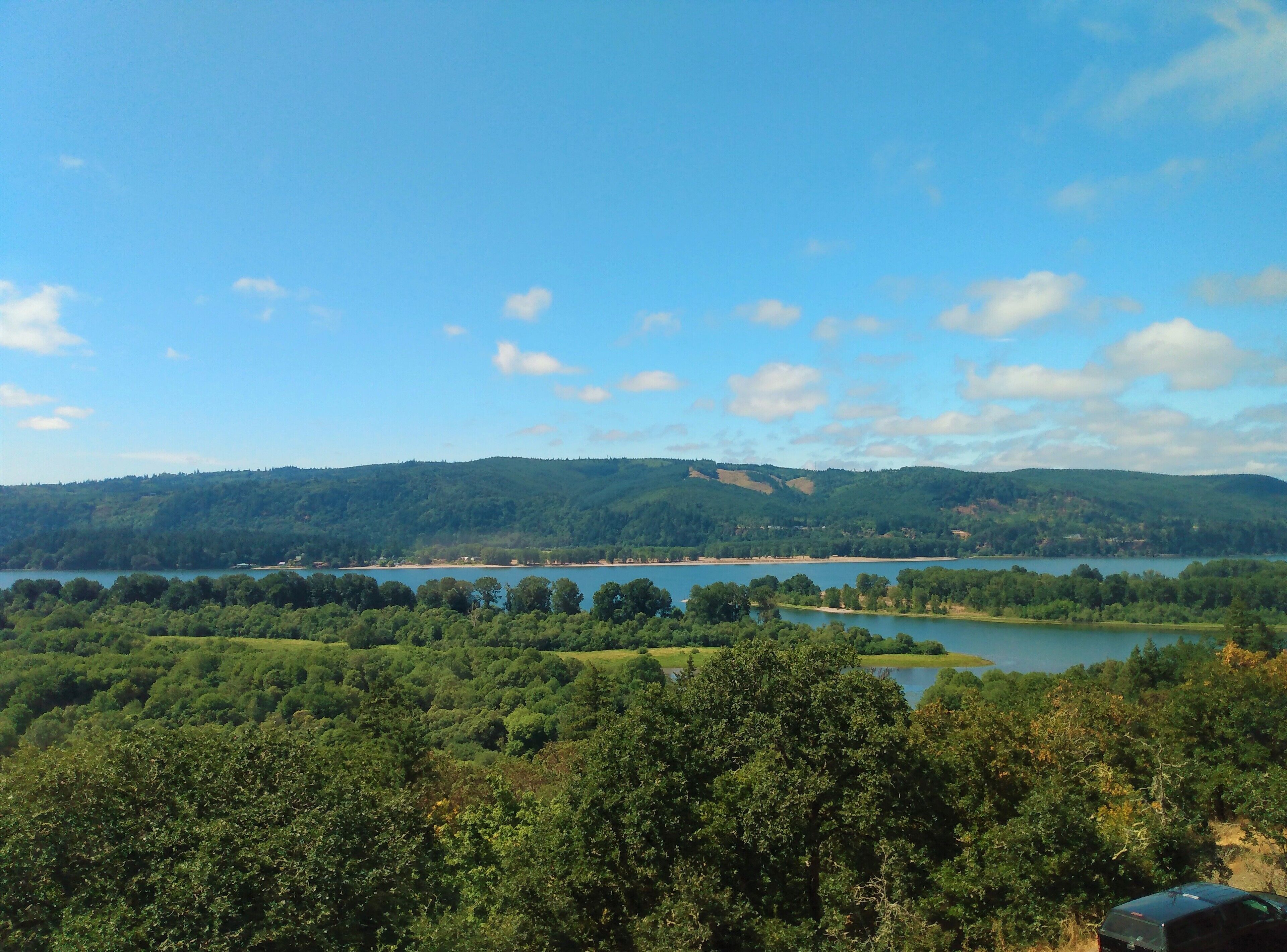 A view of a lake surrounded by dense forest and hills.