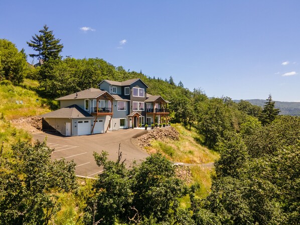 A multi-story house with a garage, a covered porch, and a driveway. - Perched on the Edge! Stunning Bluff with Wide River Views  @ Kalama Oaks Lodge (Kelso)