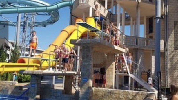 Ein Wasserpark mit einer großen Rutsche, einem Pool und einem mehrstöckigen Gebäude.