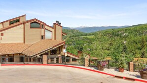 A hotel with a sloped roof, a covered entrance, and a view of a mountainous landscape. - Charming 2BR/2BA Snowmass Condo with Shared Hot Tub (Snowmass Village)