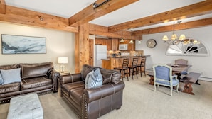 A cozy living room with a brown leather sofa, a matching ottoman, and a dining area with a wooden table and chairs. - Charming 2BR/2BA Snowmass Condo with Shared Hot Tub (Snowmass Village)
