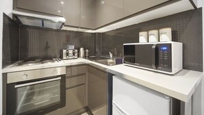 A modern kitchen with stainless steel appliances, a built-in oven, a microwave, and a coffee maker. - Studio Apartment Blue (London)
