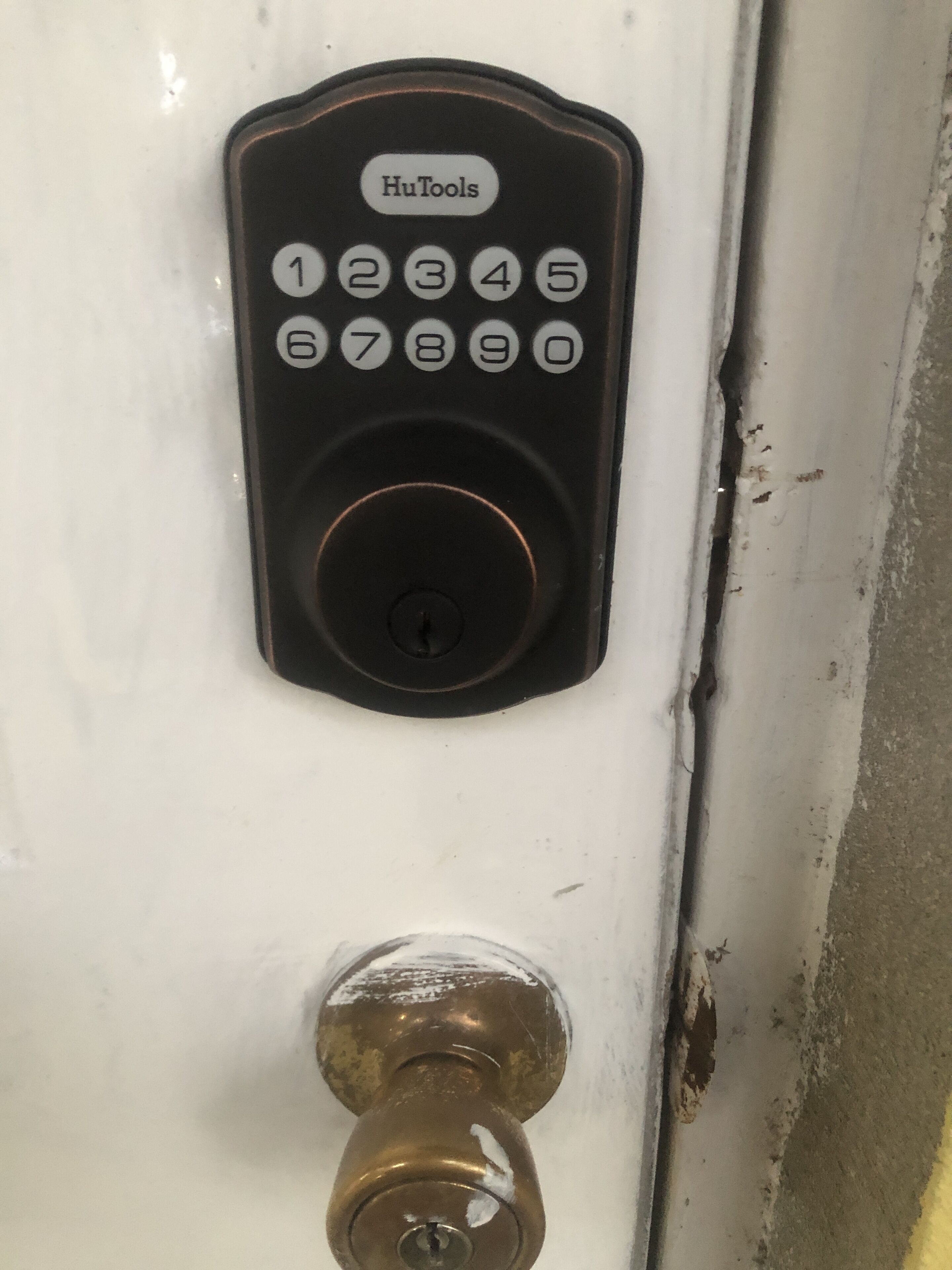 Une porte dotée d’un verrou à clavier portant l’inscription « HuTools » et d’une poignée de porte en laiton.
