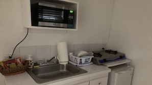 A kitchen with a microwave, sink, and a small refrigerator.