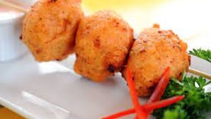 A plate of golden-brown food items, possibly kebabs, garnished with a sprig of parsley.
