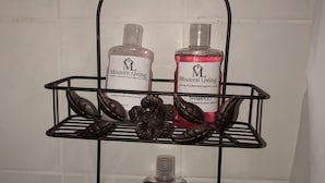 A bathroom shelf with three bottles of Modern Living products: shampoo, body wash, and conditioner.