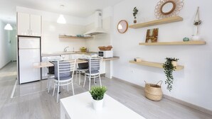 Eine moderne Küche mit weißen Schränken, einem Essbereich mit zwei Stühlen und Holzböden mit Dekorationselementen.
