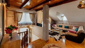 Una sala de estar acogedora con techo de madera, un conjunto de sofás, una mesa de centro y un tapete de cuero de vaca.