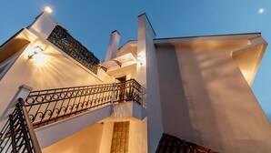 Un edificio moderno con una escalera, un balcón con barandilla metálica y la luna en el cielo.