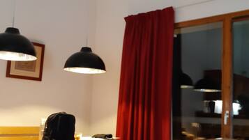 Een eetgedeelte met houten stoelen en een tafel, een rood gordijn en een opgeplakt hert boven de muur.