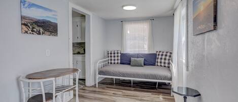 A small, compact room with a bed, a table, and a chair.