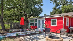 Une maison rouge avec un patio, des sièges d’extérieur et un foyer.