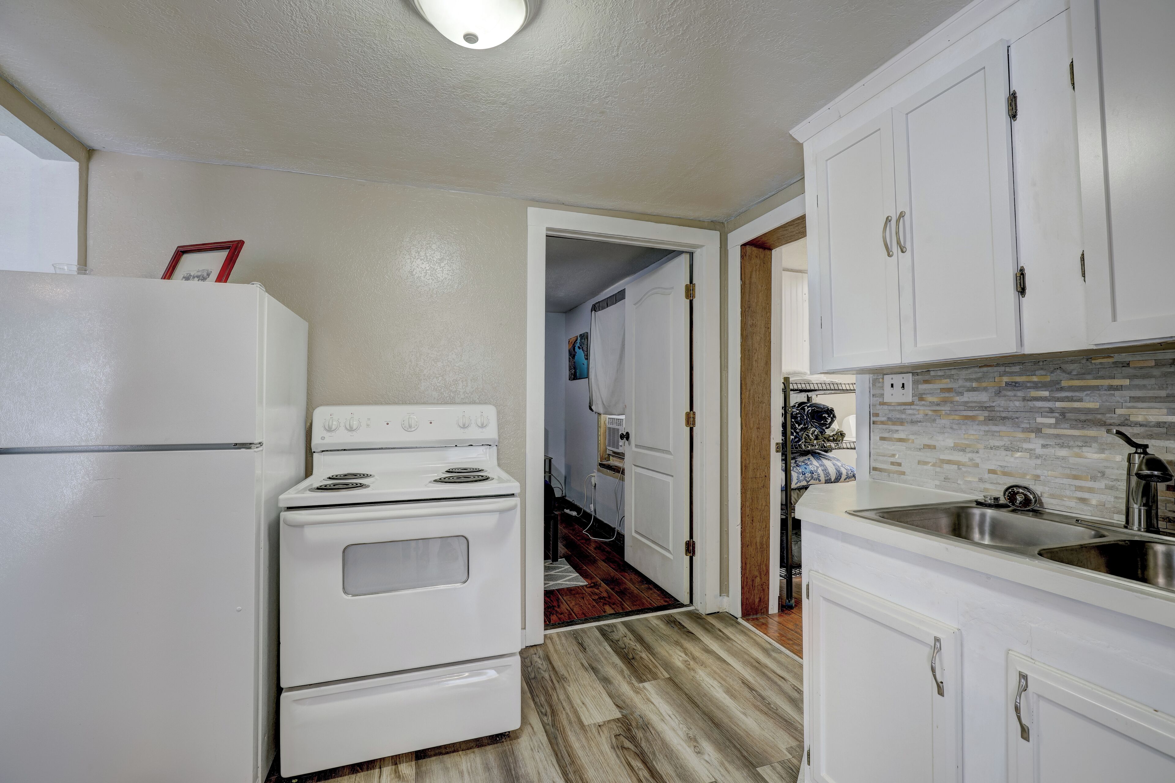 A kitchen with white cabinets, a stove, and a refrigerator.