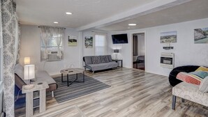 Un salon moderne avec un canapé, une petite table, un téléviseur et une cheminée.