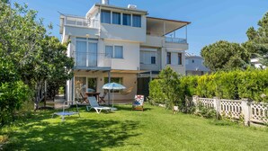 A two-story house with a balcony, a covered patio, and a well-maintained lawn. - Villa Belinda (Serik)